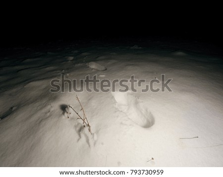 Searching of person disappeared in the winter landscape. The dim light of the headlights illuminates human footprints in deep snow.