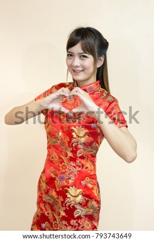 Asian woman greeting in traditional Chinese or cheongsam with hand lift welcome expression and hand is a heart symbol sent love in chinese new year celebration in red golden style
