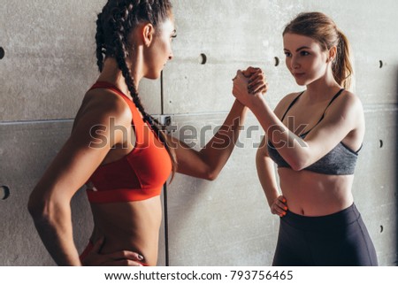 Fit women holding hands with a female opponent looking in her eyes.