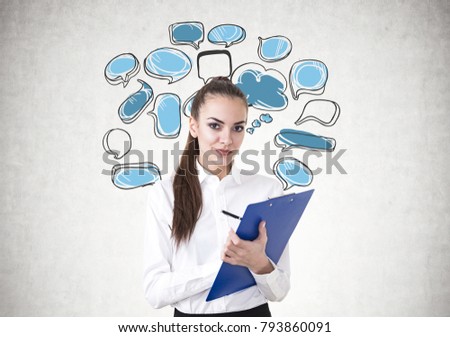 Beautiful young businesswoman wearing a white shirt, a skirt and a dark lipstick writing on a blue clipboard. A concrete wall background with blue and white speech bubbles on it. Mock up