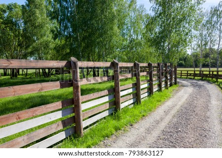 old rustic wooden fence near the asphalt road in the village, summer