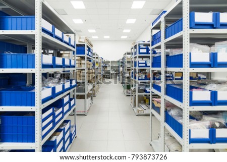 Warehouse of components for the electronics industry. White metal racks with blue plastic trays and cardboard boxes installed in them. Royalty-Free Stock Photo #793873726