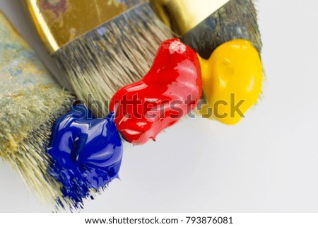 Close-up of three paint brushes with red, yellow and blue paint on a white background. Place for text, for banner, for site.