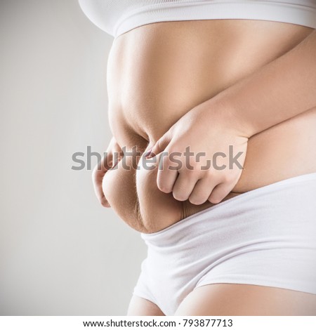 Woman in white underwear holds belly fat.