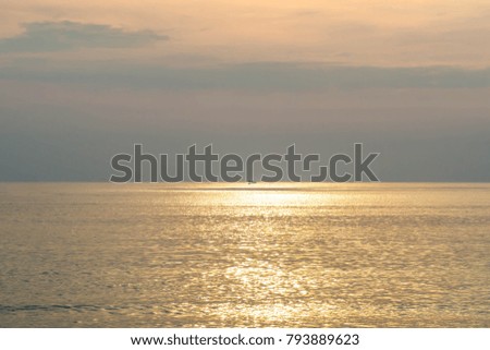 Sea and horizon with golden sky and reflection into the sea at the sunset time .