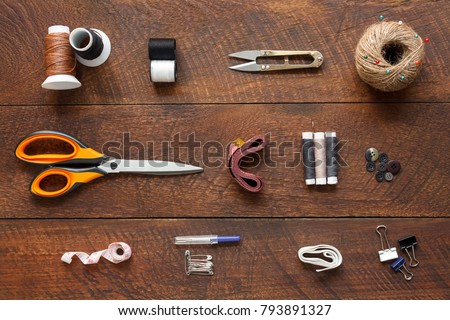 Flat lay aerial image of fashion designer items background concept.Top view sewing accessory or tailor equipment on modern rustic brown wooden at home office desk studio.Crafting tools in work shop.