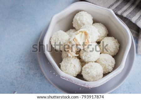 Bowl with coconut candies on blue concrete table background. Close up