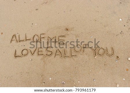 Handwriting  words "ALL OF ME LOVES ALL OF YOU." on sand of beach.
