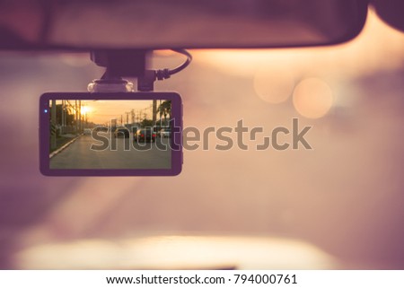 Close up car on highway at sunset, with video recorder next to a rear view mirror, video recorder driving a car on highway, car video recorder, Full HD camera recorder for vehicle.