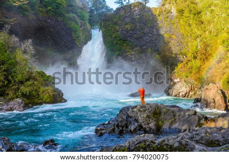 A man takes a picture of waterfall in the biological reserve Huilo-Huilo in Chile 
