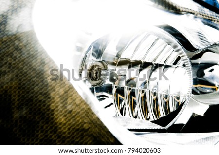 Abstract close-up of a modern motorcycle headlight with carbon-fiber fairing and broken reflections. 