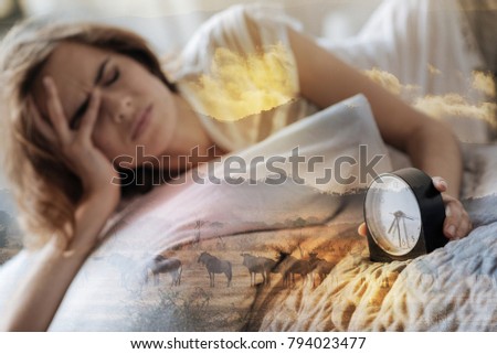 Bad dreams. Tired woman pressing lips and wrinkling forehead while leaning head on right hand