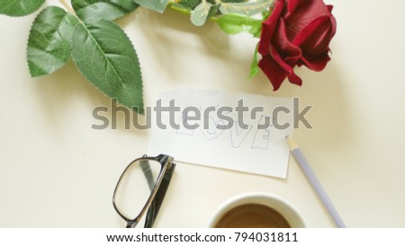 A cup of coffee ,red rose ,glasses,paper and pencil on the white background.