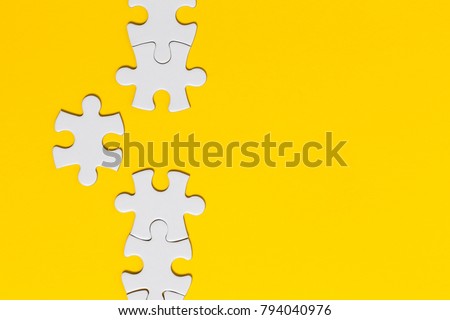 White jigsaw puzzle pieces on a yellow background. Business solution concept