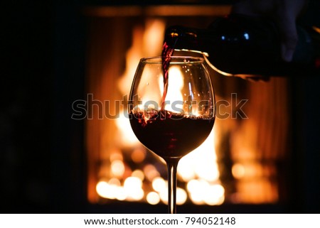 In winter, before the fireplace, is poured, tasted red wine in a glass. Concept of: relax, restaurant, wine, sommelier.