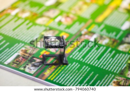 Black magnifying glass on colourfuk printed paper. Industrial printing process.