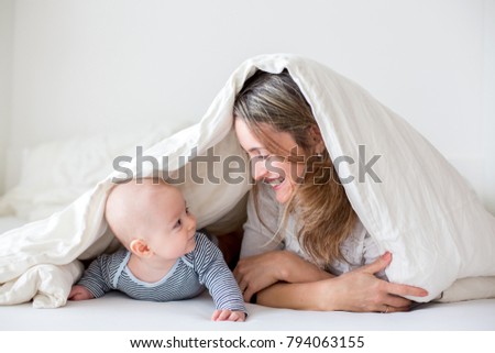 Mother and her little baby boy, playing together in bedrroom, happy family concept
