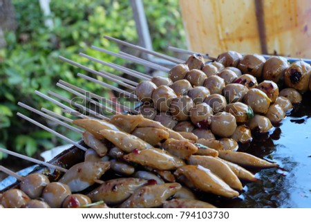image of dump of  Thai meat ball and sausage sticks deep in Thai spicy sauce. focus picture with some sticks and blur other composition.concept popular street food in Thailand