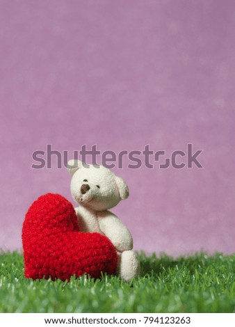 Teddy bear holding a handmade red heart on green grass background is royal pink.Copy space for text, Valentines day, love concept and love background