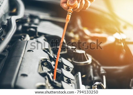 Mechanic repairing car with open hood,Side view of mechanic checking level motor oil in a car with open hood Royalty-Free Stock Photo #794133250