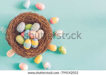 Coloeful easter eggs in nest on pastel color background with space.