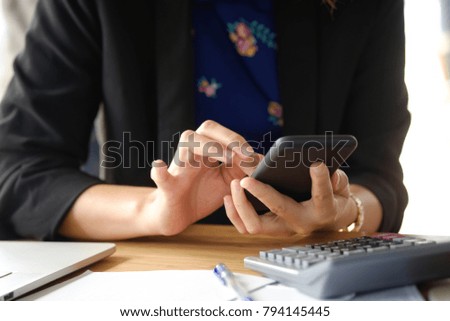 Closeup shot of an unidentifiable woman using a mobile phone at desk.