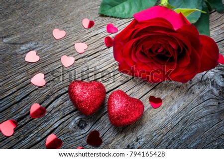 Valentines Day concept with red rose, glitter and paillette hearts on the rustic wooden background, copy space.