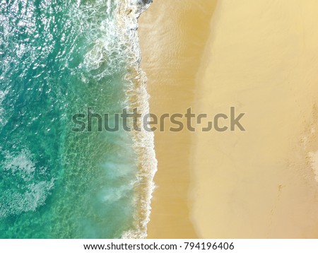 Sand beach aerial, top view of a beautiful sandy beach aerial shot with the blue waves rolling into the shore, some rocks present