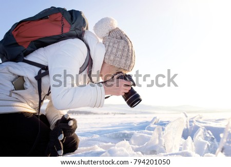 Portrait of female photographer shooting winter landscape next to the frozen lake Baikal. Winter tourism in Russia
