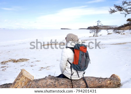 Travel concept. Female hiker with backpack enjoing view of Lake Baikal, Siberia, Russia. Winter tourism.