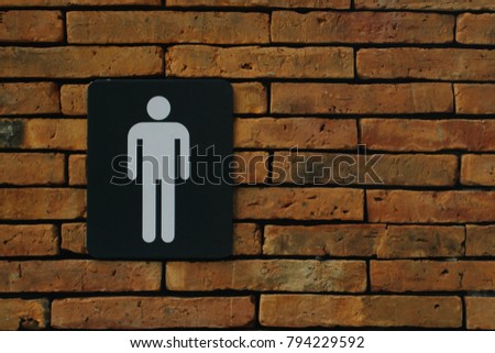 Male toilet symbol on brick wall. Copy space.