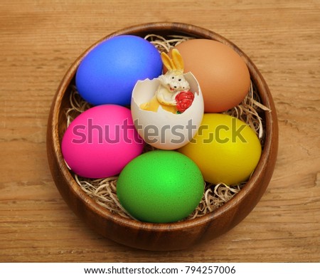 Easter table. Top view of Easter brown and white eggs on wooden plates and Easter rabbit inside shell lying on wooden rustic table with hay