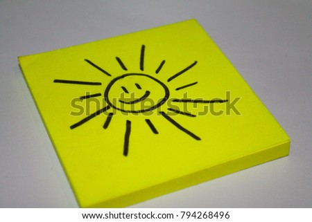

close up of a sun on a yellow post it which is inclined to the left