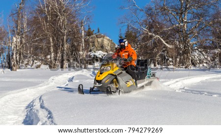 Athlete on a snowmobile moving in the winter forest in the mountains of the Southern Urals.
