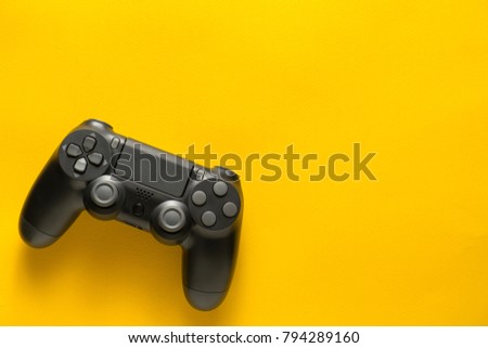 black gamepad on a yellow background. Gaming concept