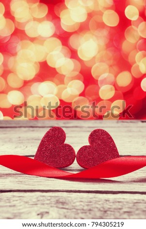 Valentine background with handmade glitter hearts and ribbon on rustic wood with holiday lights bokeh background, copy space. Valentine's Day, love, romantic concept. Vertical orientation