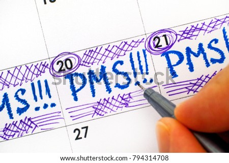 Woman fingers with pen writing reminder PMS in calendar. Close-up. Royalty-Free Stock Photo #794314708