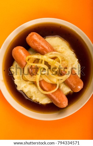 Traditional Scandinavian Style Sausage And Mashed Potatoes With Gravy And Fried Onions, With No People, Against An Orange Background