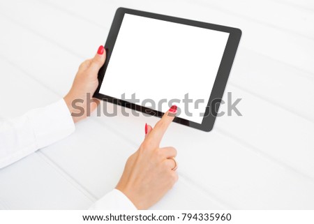 Woman using tablet with white blank screen on white desk