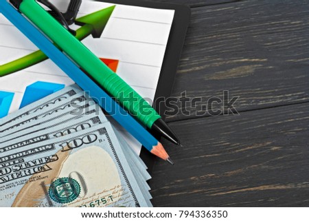 American dollars, pencils and a chart on a wooden background. Business concept.