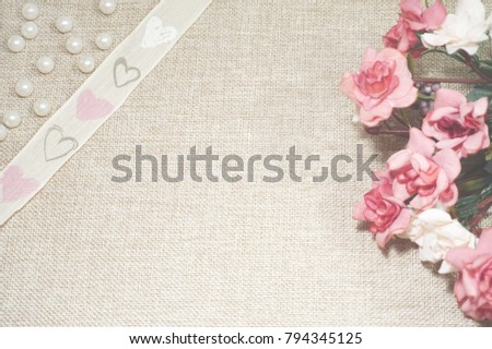 Roses, pearls and decorative band with hearths on the jute background. A bouquet of roses, pearls and a heart from a wicker on jute