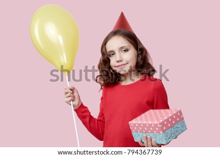 People, joy, birthday, fun, family holiday. Picture a quiet child who made a gift to her family & friends. Studio portrait isolated on a pink background.