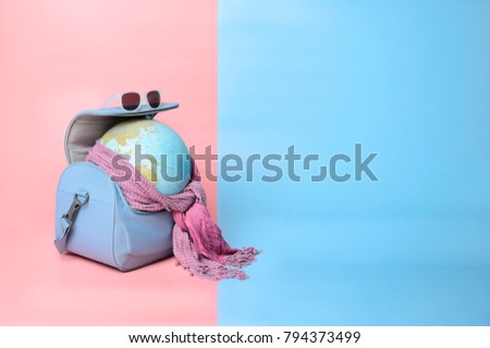 Travelling globe going on vacation in travel bag with sunglasses and scarf on soft pink and light blue pastel colored background, space for text Royalty-Free Stock Photo #794373499