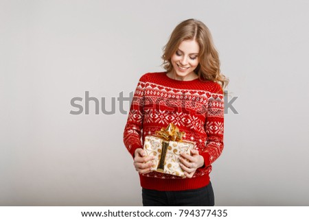 Happy beautiful girl in a fashion stylish red sweater holding a gift