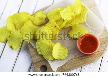 Potato chips on a wooden tray on a white table
