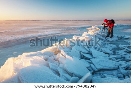Photographer take pictures on the river coast in winter time