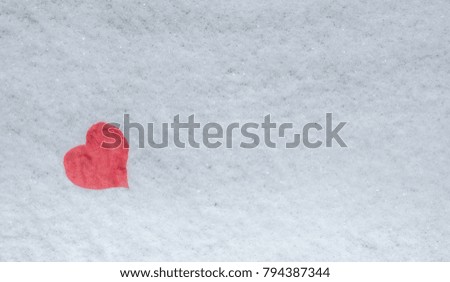 Red heart on ice and snow