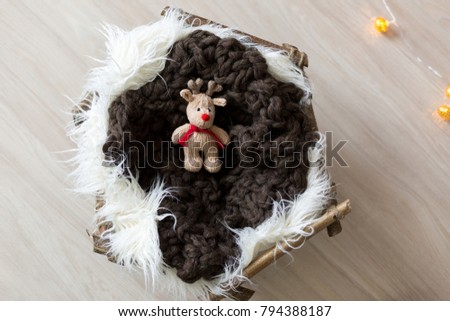 wooden basket with white fur and a knitted toy. deer toy
