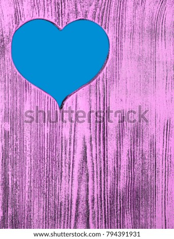 The blue heart is carved in a wooden board of purple. Background.