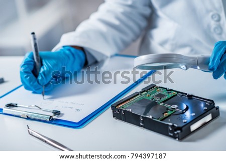 Forensic science expert examining hard drive Royalty-Free Stock Photo #794397187